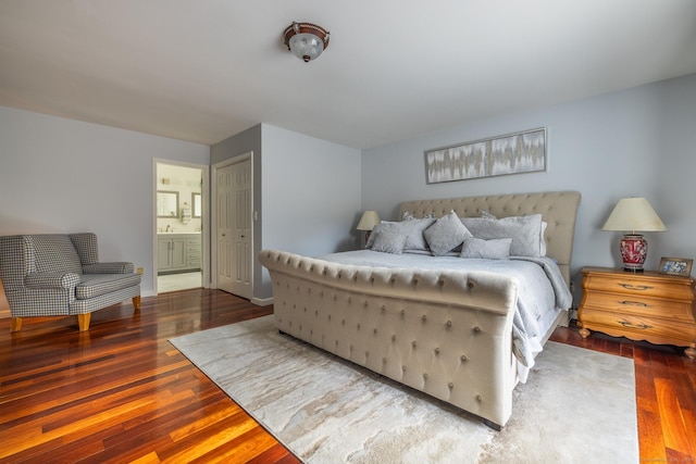 bedroom featuring ensuite bathroom, dark hardwood / wood-style flooring, and sink