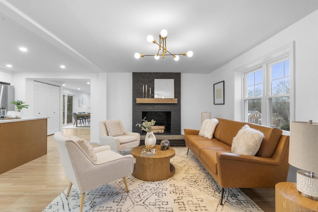 living room with light wood-type flooring, a fireplace, and a chandelier