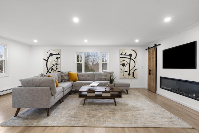 living room with a barn door, light hardwood / wood-style floors, and ornamental molding