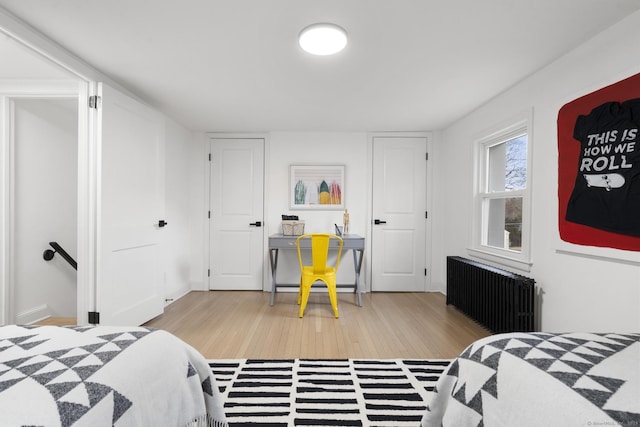 bedroom featuring radiator heating unit and light hardwood / wood-style floors