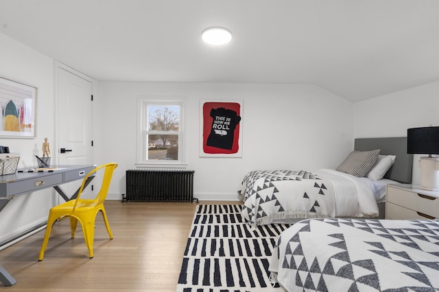 bedroom featuring hardwood / wood-style floors, radiator heating unit, and vaulted ceiling