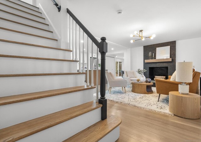 stairway with a fireplace, hardwood / wood-style floors, and a chandelier