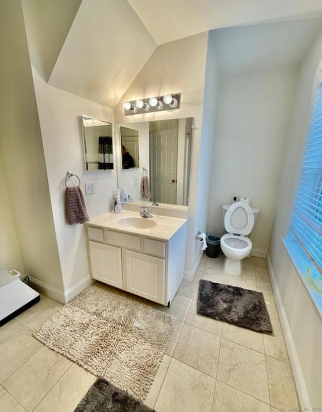 bathroom featuring tile patterned flooring, vanity, toilet, and lofted ceiling