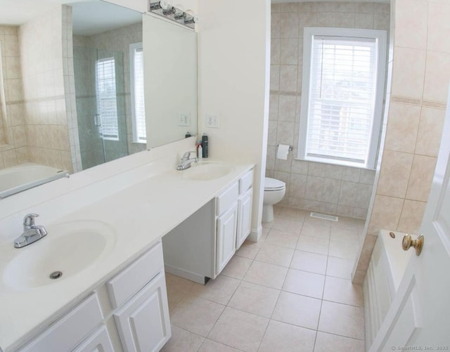 bathroom with tile patterned floors, vanity, a healthy amount of sunlight, and tile walls