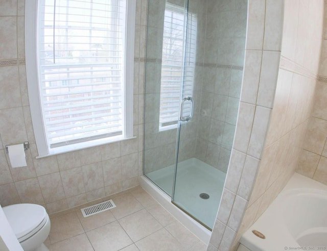 bathroom featuring toilet, tile patterned flooring, tile walls, and shower with separate bathtub