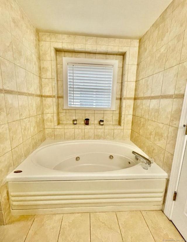 bathroom with tile patterned flooring, a bathtub, and tile walls