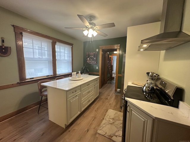 kitchen with light stone countertops, range with electric cooktop, ceiling fan, exhaust hood, and light wood-type flooring