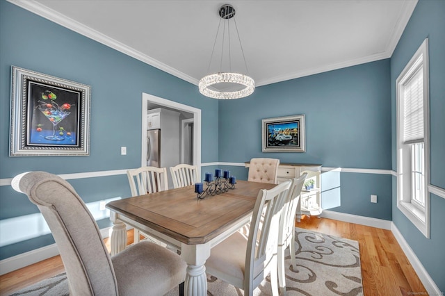 dining area with an inviting chandelier, a wealth of natural light, light hardwood / wood-style floors, and crown molding