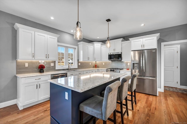 kitchen with sink, a center island, white cabinetry, pendant lighting, and appliances with stainless steel finishes