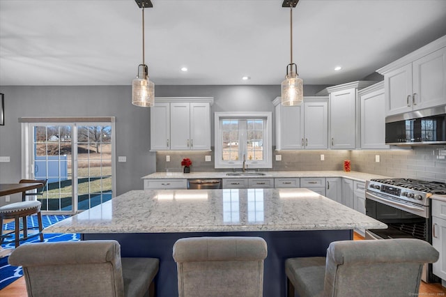 kitchen featuring white cabinets, stainless steel appliances, and decorative light fixtures