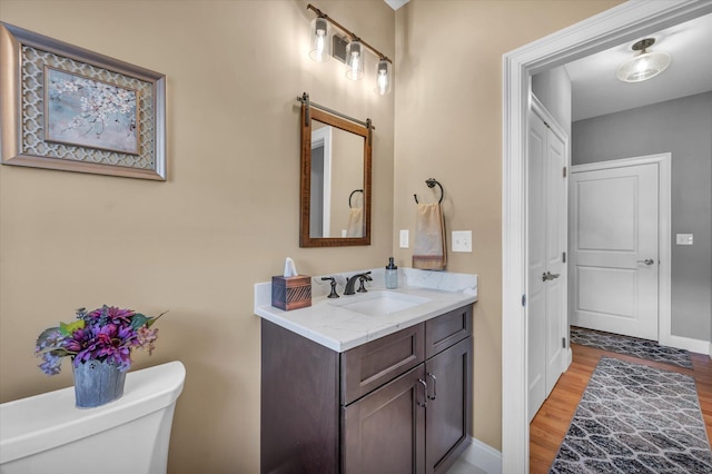 bathroom featuring toilet, vanity, and hardwood / wood-style flooring