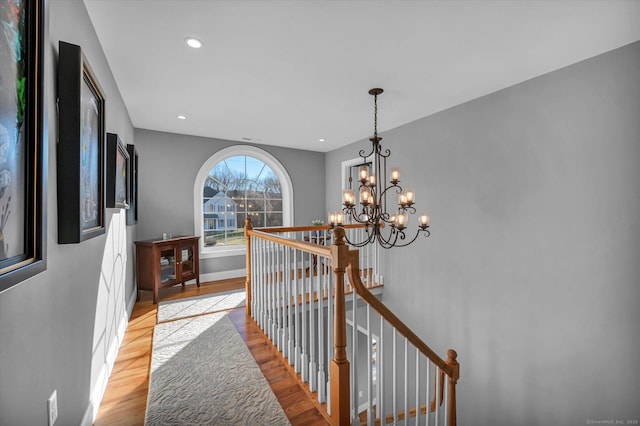 hallway with light wood-type flooring and a chandelier