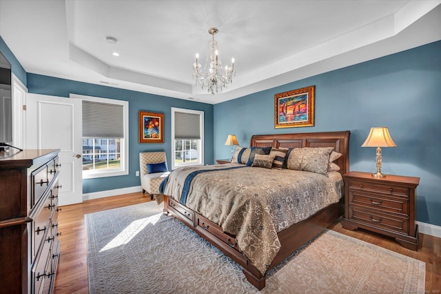 bedroom featuring hardwood / wood-style flooring, a raised ceiling, and a chandelier