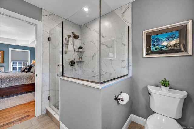 bathroom featuring hardwood / wood-style floors, a shower with shower door, and toilet