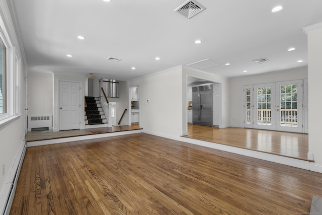 unfurnished living room featuring visible vents, radiator, ornamental molding, baseboard heating, and wood finished floors