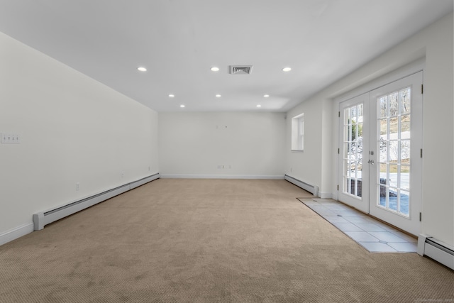 empty room featuring a baseboard heating unit, light colored carpet, and visible vents