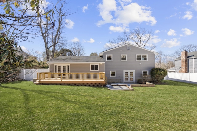 rear view of house featuring a hot tub, a wooden deck, a lawn, french doors, and a fenced backyard