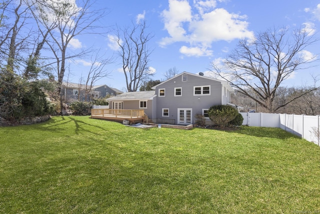 back of property with a fenced backyard, a lawn, french doors, and a deck