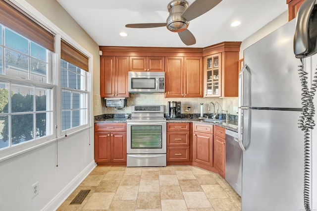 kitchen with a healthy amount of sunlight, stainless steel appliances, dark stone countertops, and sink