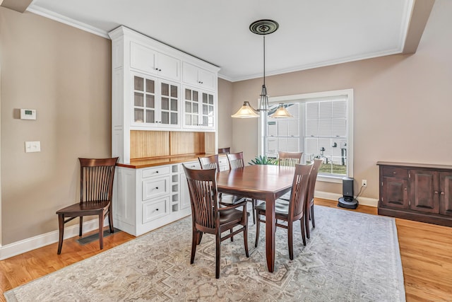 dining area featuring crown molding, light hardwood / wood-style floors, and an inviting chandelier