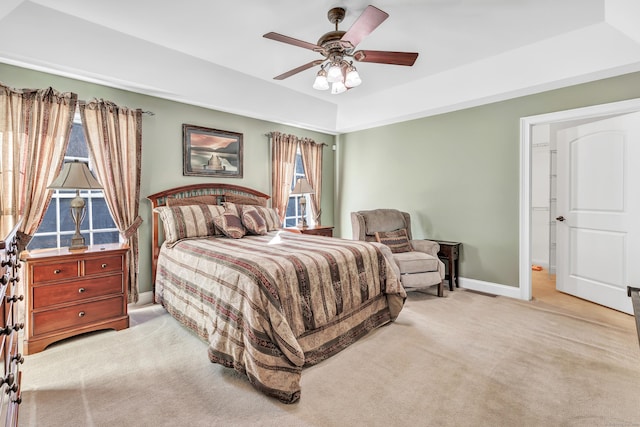 carpeted bedroom featuring ceiling fan and a raised ceiling