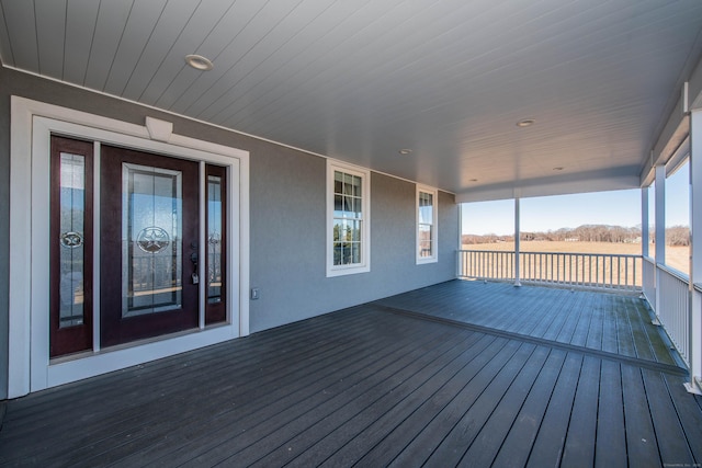 deck featuring covered porch and a rural view