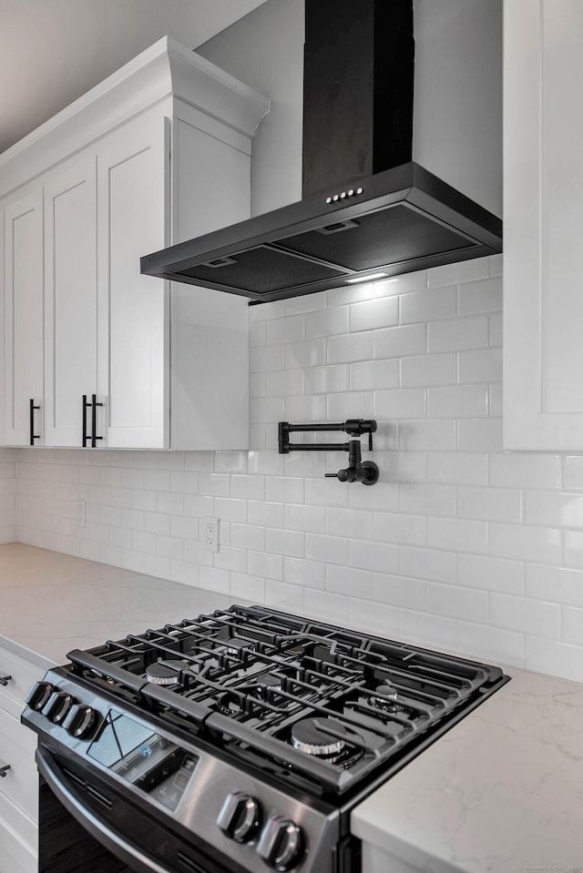 kitchen with tasteful backsplash, white cabinetry, wall chimney exhaust hood, and light stone counters