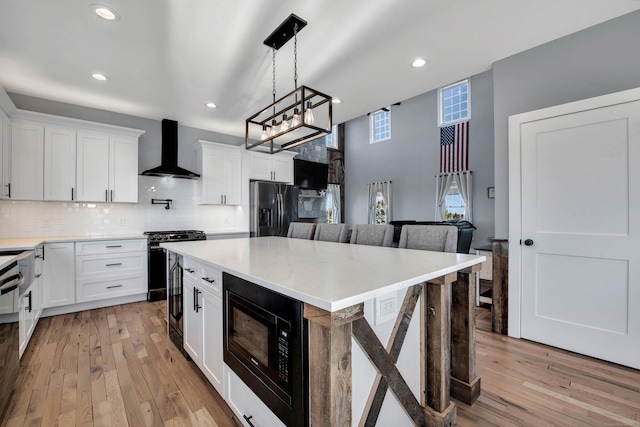 kitchen with wall chimney exhaust hood, white cabinetry, black microwave, and stainless steel refrigerator with ice dispenser