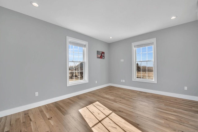 spare room featuring a healthy amount of sunlight and light hardwood / wood-style flooring