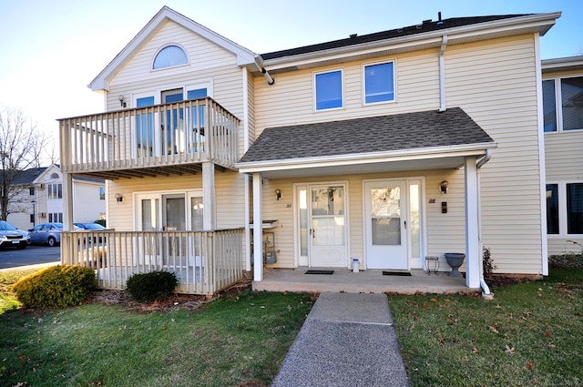 multi unit property with covered porch, a balcony, and a front lawn