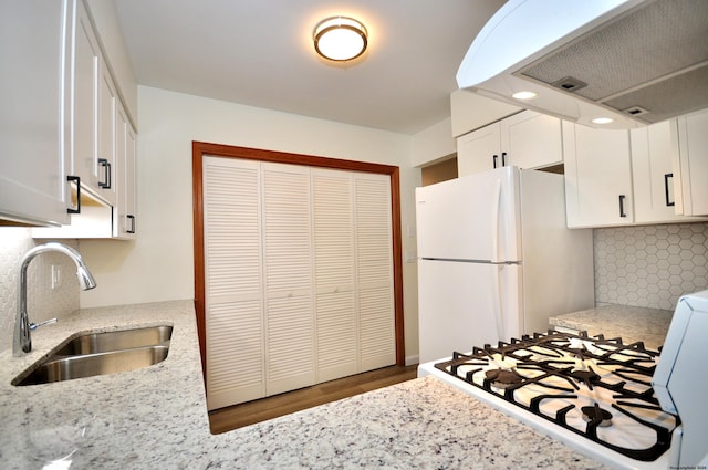 kitchen with white appliances, extractor fan, white cabinetry, and sink