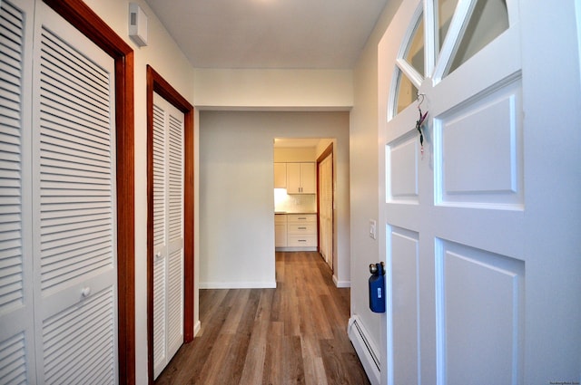 corridor with baseboard heating and hardwood / wood-style floors