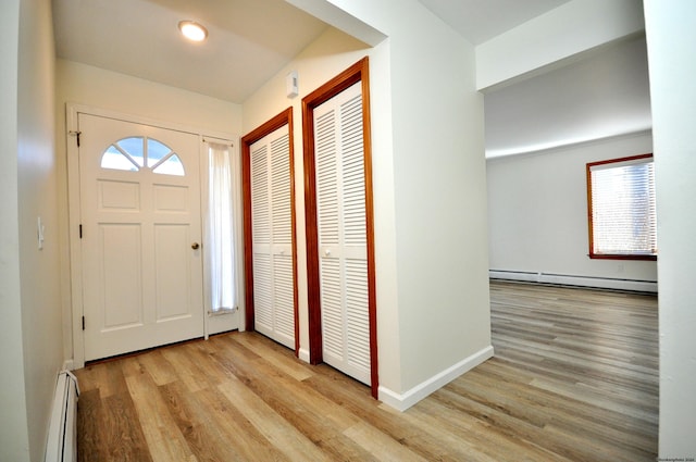 entrance foyer featuring baseboard heating, light hardwood / wood-style floors, and a wealth of natural light