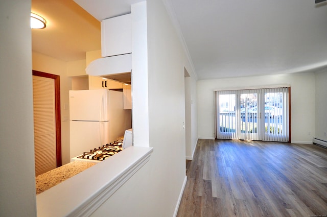 kitchen with white refrigerator, white cabinetry, hardwood / wood-style floors, range, and crown molding