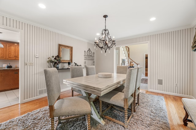 dining space with crown molding, a chandelier, and light wood-type flooring