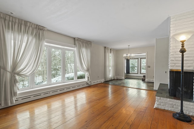 unfurnished living room with a multi sided fireplace, a wealth of natural light, a baseboard radiator, and hardwood / wood-style flooring