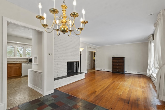 unfurnished living room with ornamental molding, a brick fireplace, baseboard heating, and a notable chandelier