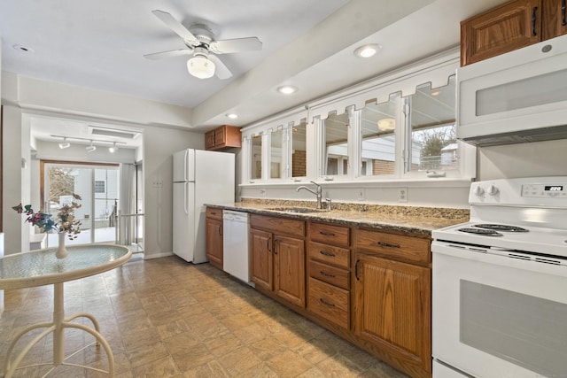 kitchen with ceiling fan, sink, dark stone counters, track lighting, and white appliances