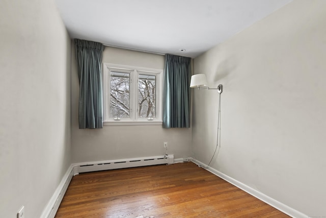 unfurnished room featuring hardwood / wood-style flooring and a baseboard heating unit