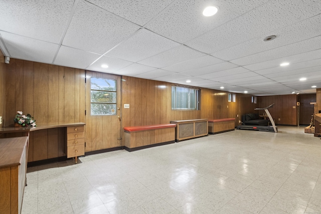 interior space featuring a drop ceiling and wooden walls