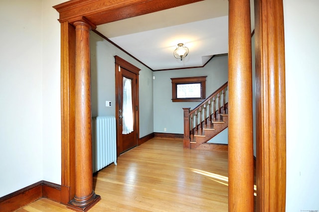 entrance foyer with ornamental molding, radiator heating unit, light hardwood / wood-style floors, and ornate columns