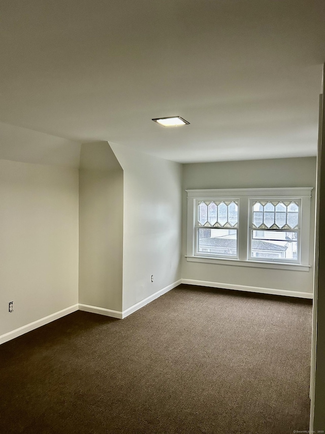 spare room featuring dark carpet