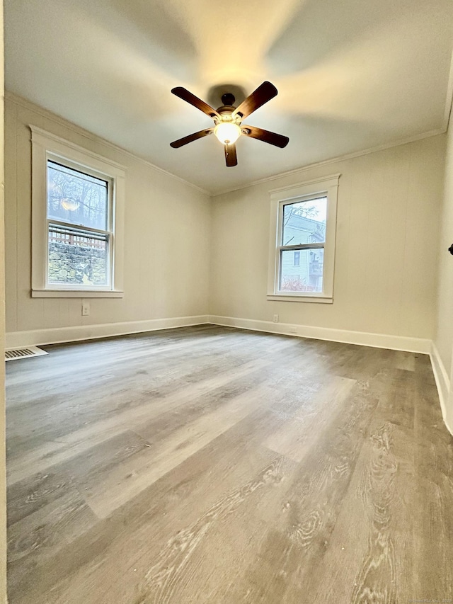 spare room featuring a wealth of natural light, ceiling fan, crown molding, and wood-type flooring