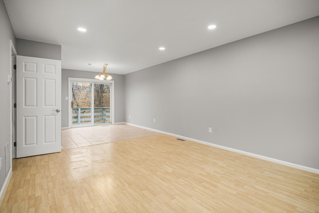 empty room with a chandelier and light hardwood / wood-style flooring