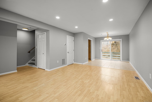 spare room with light hardwood / wood-style floors and an inviting chandelier