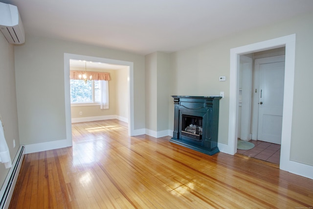 unfurnished living room featuring hardwood / wood-style floors, baseboard heating, a wall mounted AC, and a notable chandelier