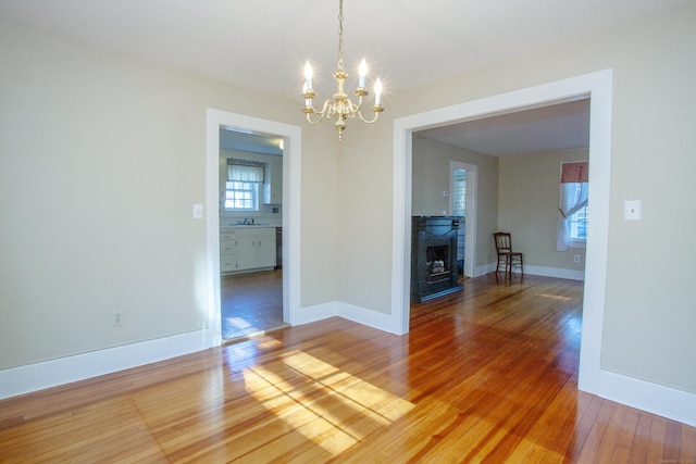 unfurnished dining area featuring a chandelier, wood-type flooring, and plenty of natural light