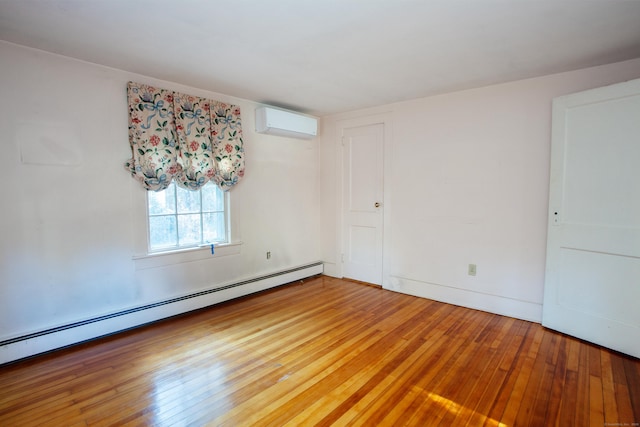 empty room with baseboard heating, hardwood / wood-style flooring, and an AC wall unit