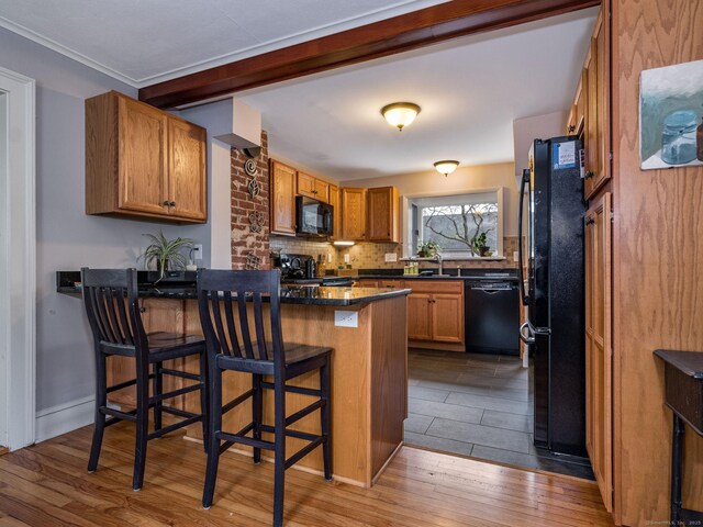 kitchen featuring hardwood / wood-style floors, black appliances, decorative backsplash, a kitchen bar, and kitchen peninsula