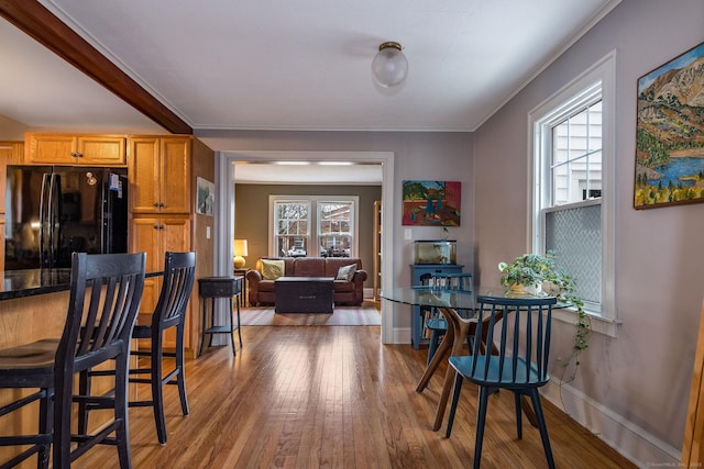 kitchen with black refrigerator, hardwood / wood-style flooring, and ornamental molding